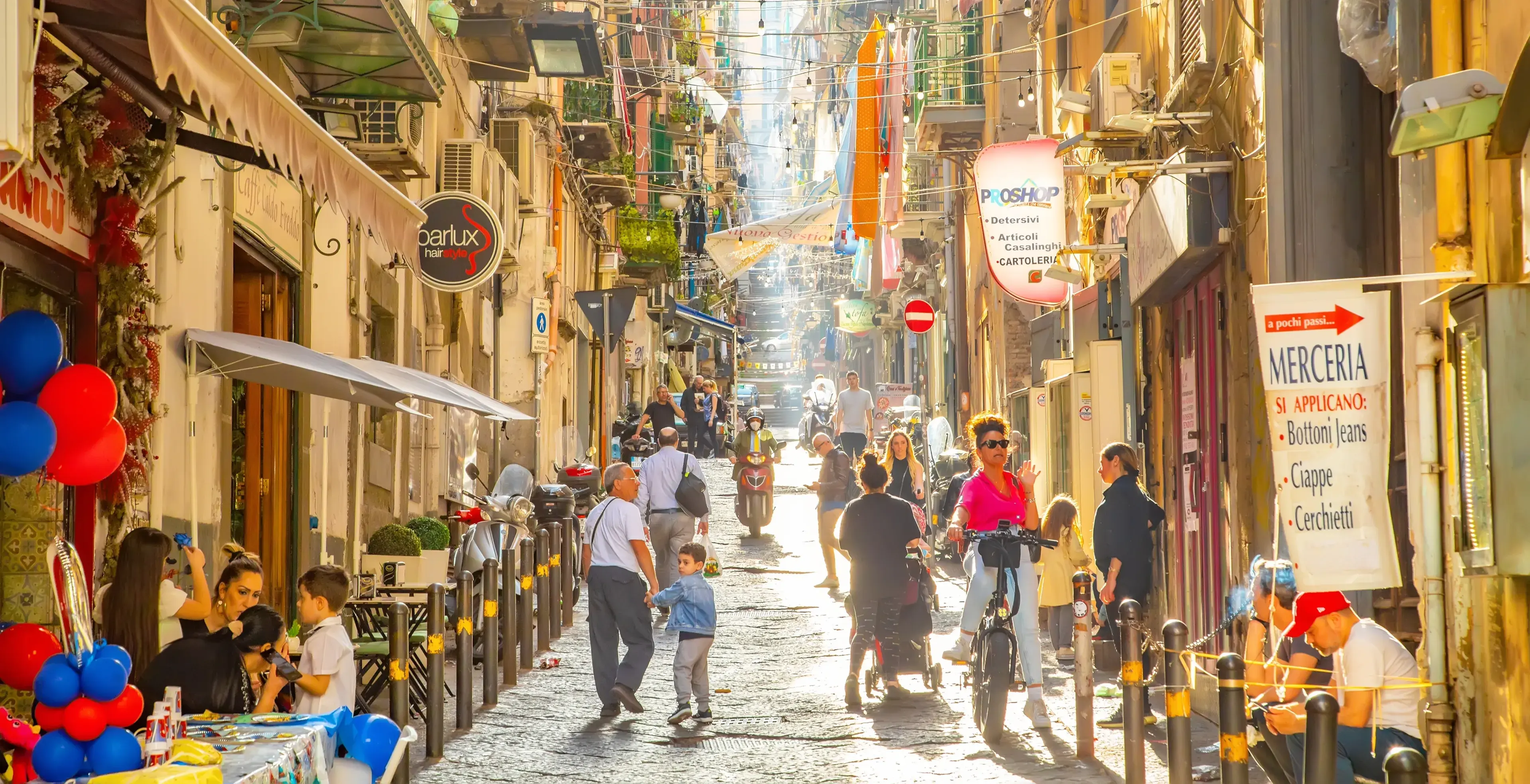 Naples, Italy - 10 June, 2022: Sunny narrow street in Napoli old town, colorful Spagnoli (Spanish) quarter. Italian busy city life in Naples city, people walking down the street. Naples, Italy - 10 June, 2022: Sunny narrow street in Napoli old town, colorful Spagnoli (Spanish) quarter. Italian busy city life in Naples city, people walking down the street.