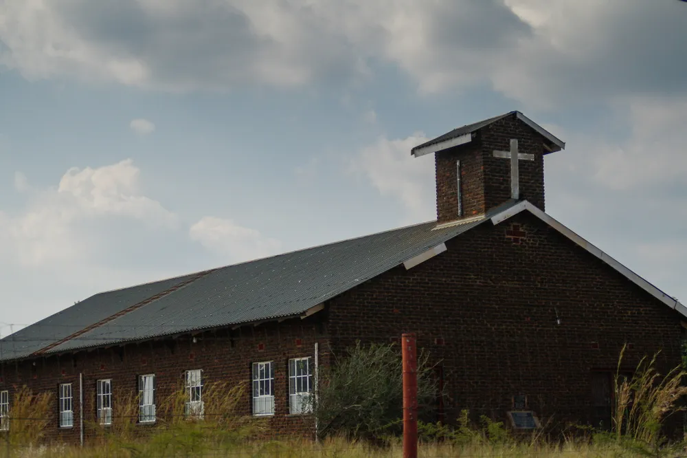 Klerksdorp, North West Province / South Africa - May 01 2018: Brown Brick Church with blue sky and clouds in a rural area with windows, religion