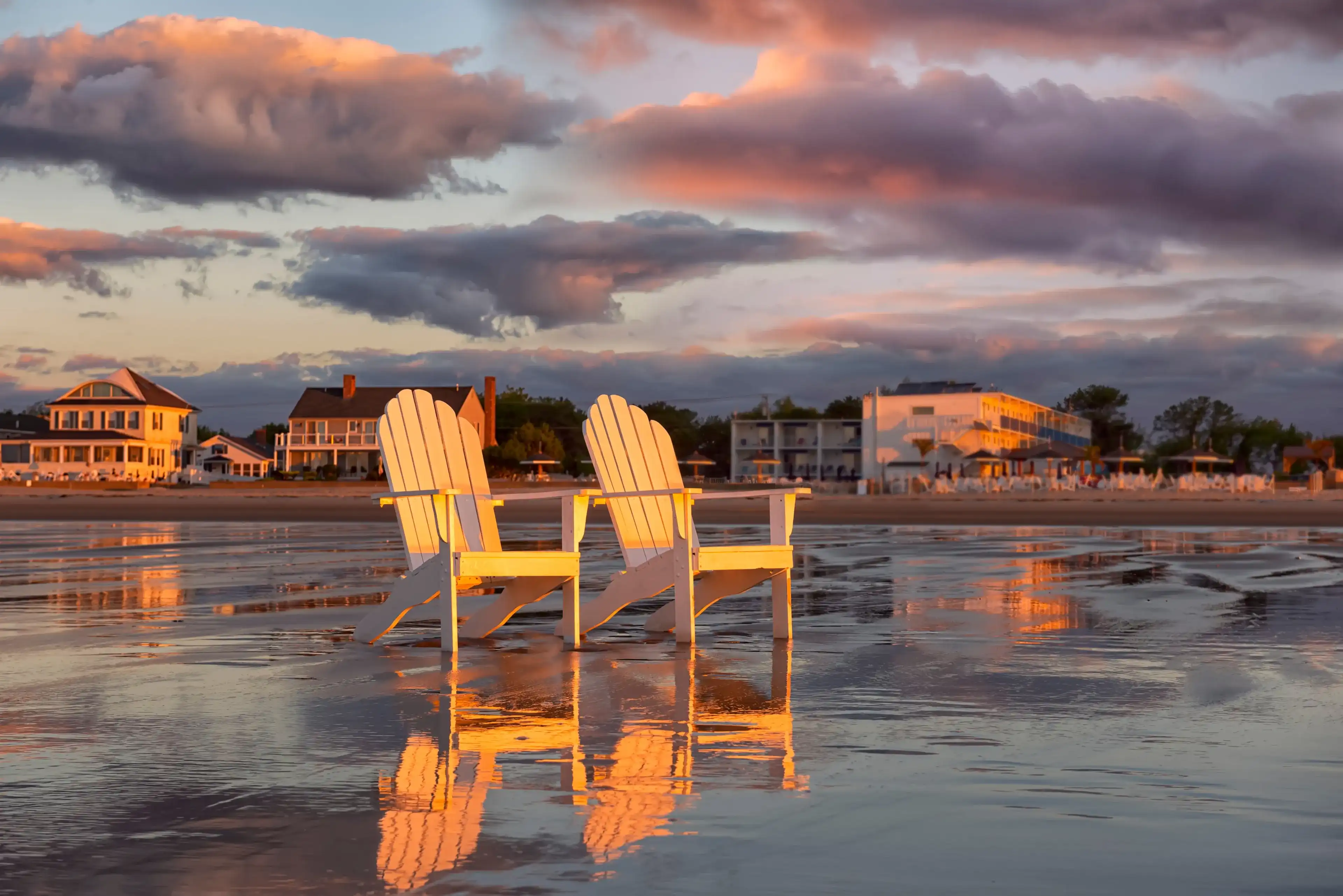 Two wooden traditional armchairs on a sandy beach at sunrise overlooking the coastline. Atlantic Ocean. USA. Maine. Old Orchard Beach. Two wooden traditional armchairs on a sandy beach at sunrise overlooking the coastline. Atlantic Ocean. USA. Maine. Old Orchard Beach.