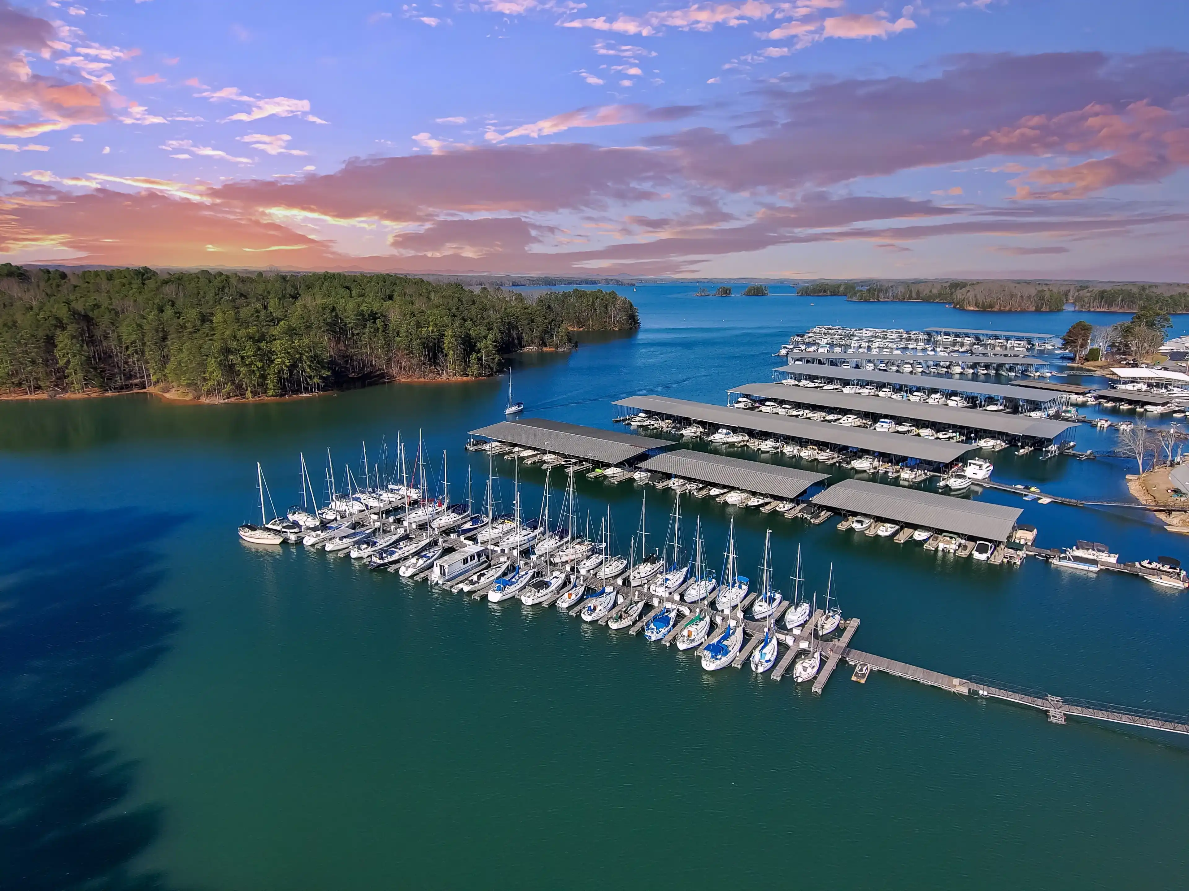 Boats and yachts docked and sailing in the marina on Lake Lanier with lush green trees and and powerful clouds at sunset in Cummings Georgia USA Boats and yachts docked and sailing in the marina on Lake Lanier with lush green trees and and powerful clouds at sunset in Cummings Georgia USA