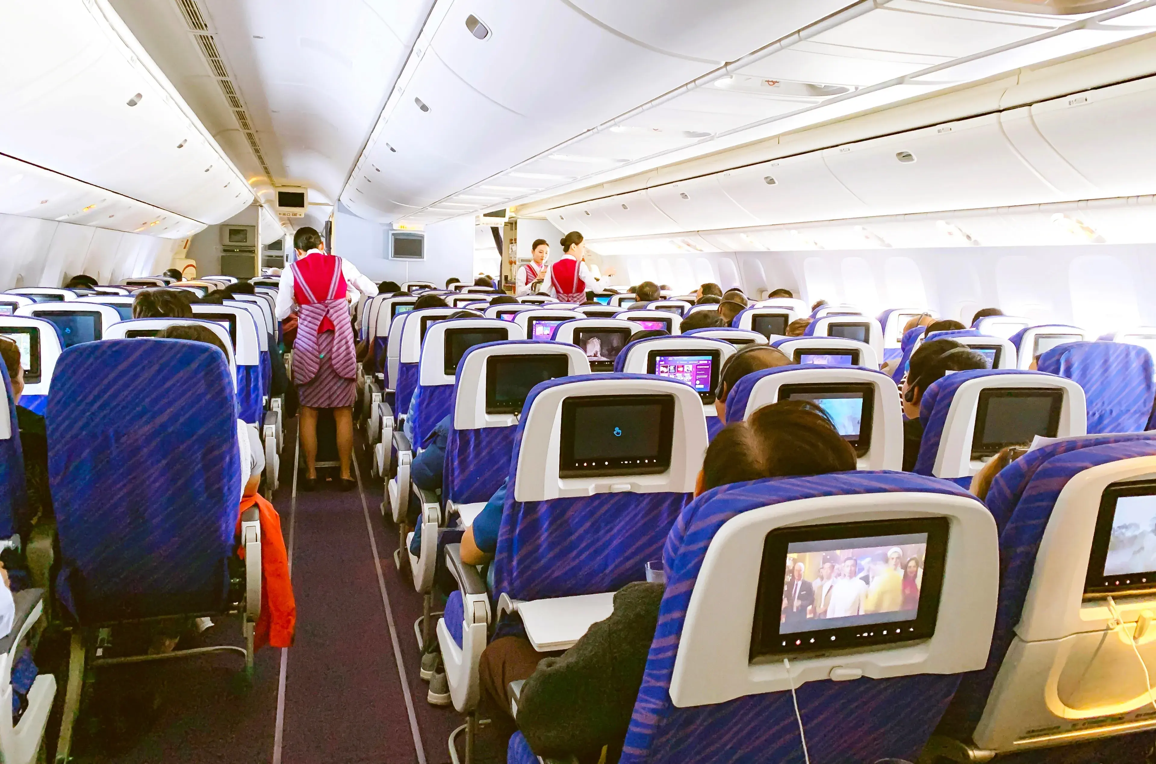 Beijing, China - November 5, 2019 : Inside Of A Commercial Airplane With Passengers On Seats And Flight Attendant Serving Food On Aisle. Beijing, China - November 5, 2019 : Inside Of A Commercial Airplane With Passengers On Seats And Flight Attendant Serving Food On Aisle.