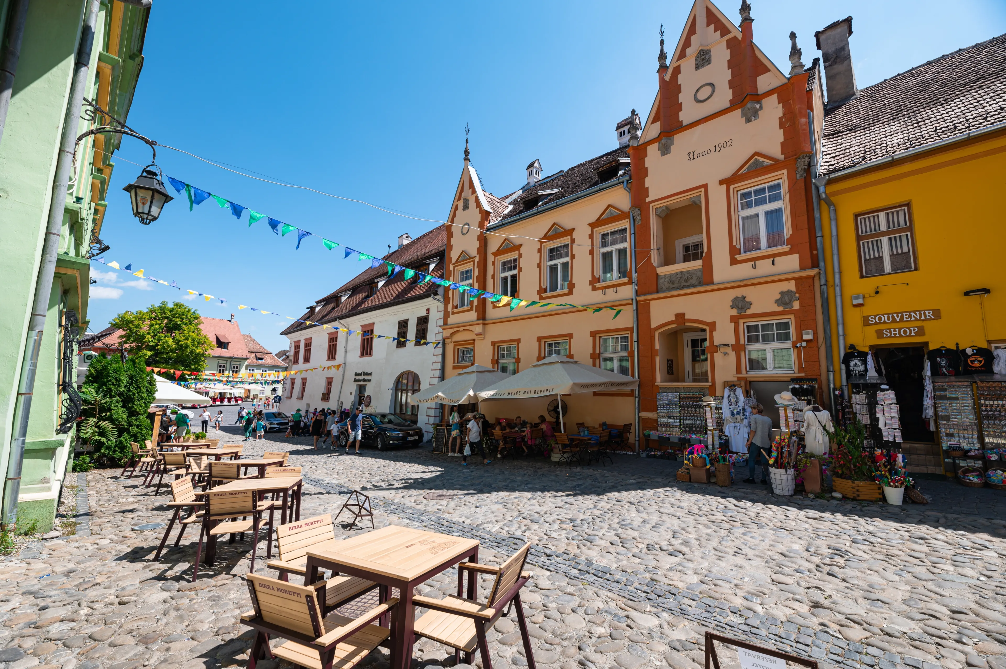 Sighișoara, Romania - July 2022: Old street with cobble stones and light colored ancient buildings in the medieval center of Sighișoara in Transylvania, Romania.