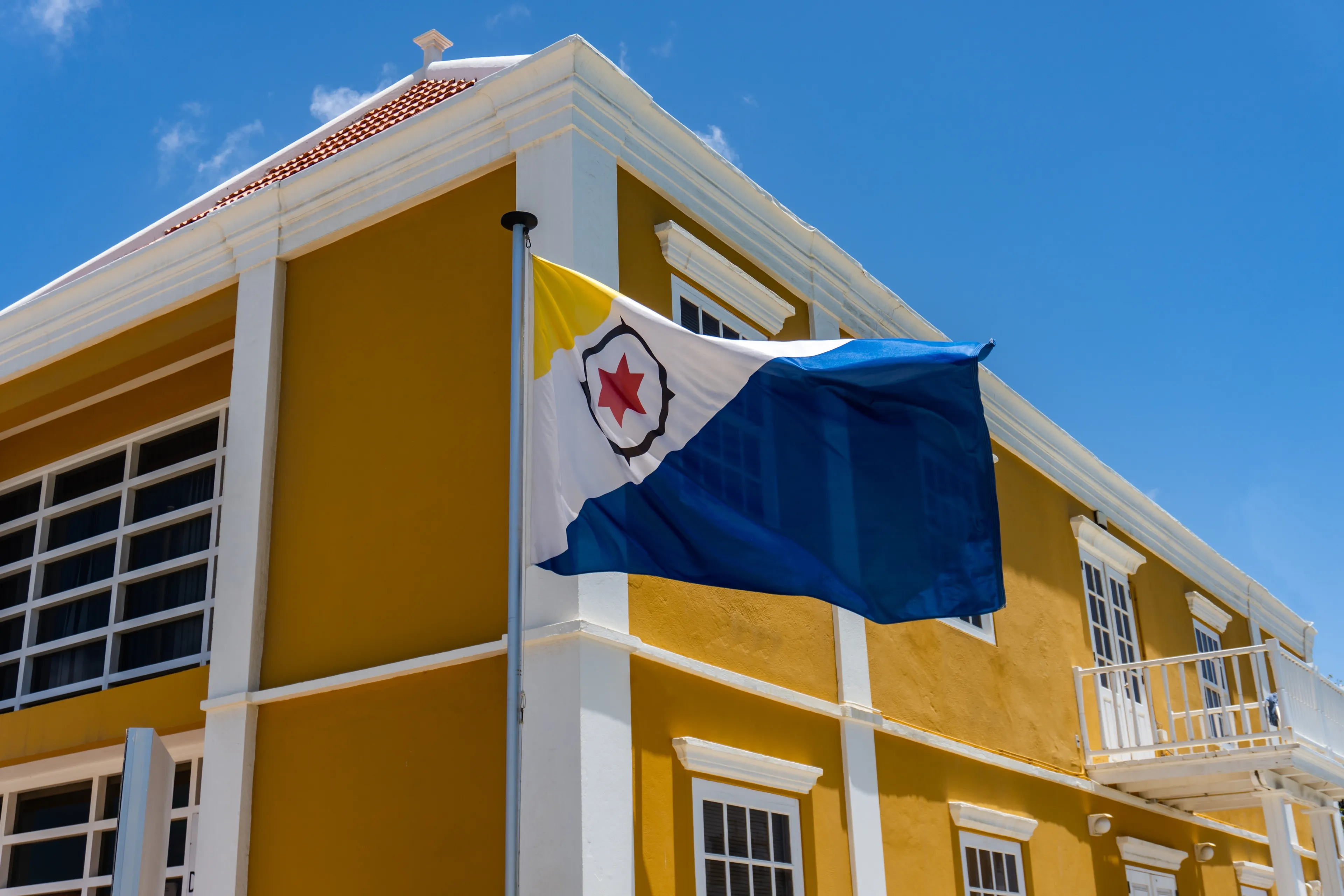Kralendijk, Bonaire, Caribbean Netherlands: Douanekantoor - Customs Office and flag of Bonaire. Black compass, red six-pointed star, dark blue and yellow triangles.