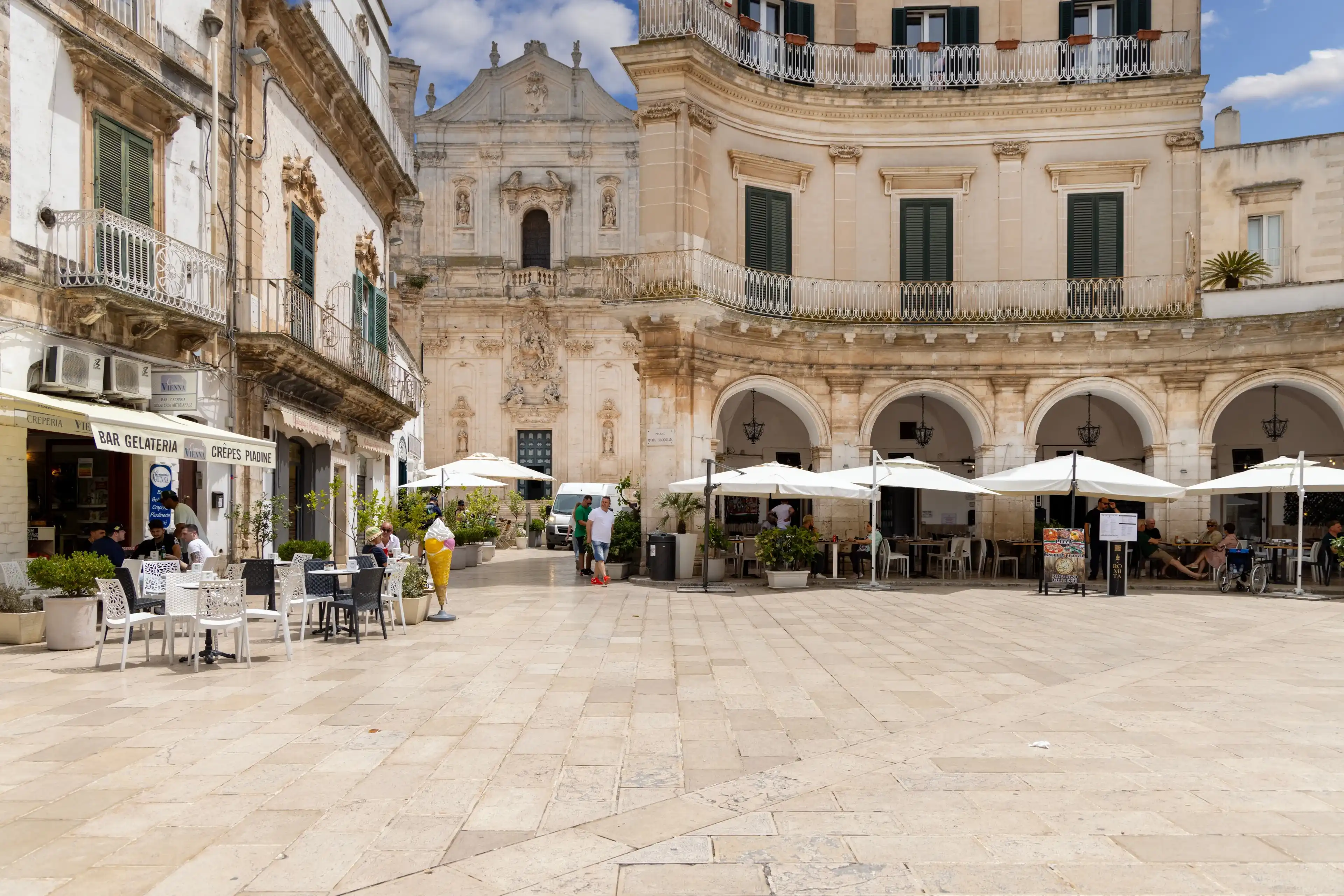 Martina Franca, Italy, Apulia - May 25, 2024: Maria Immaculate Square (Piazza Maria Immacolata), historical portici in neoclassical style. Basilica of San Martino in a distance Martina Franca, Italy, Apulia - May 25, 2024: Maria Immaculate Square (Piazza Maria Immacolata), historical portici in neoclassical style. Basilica of San Martino in a distance