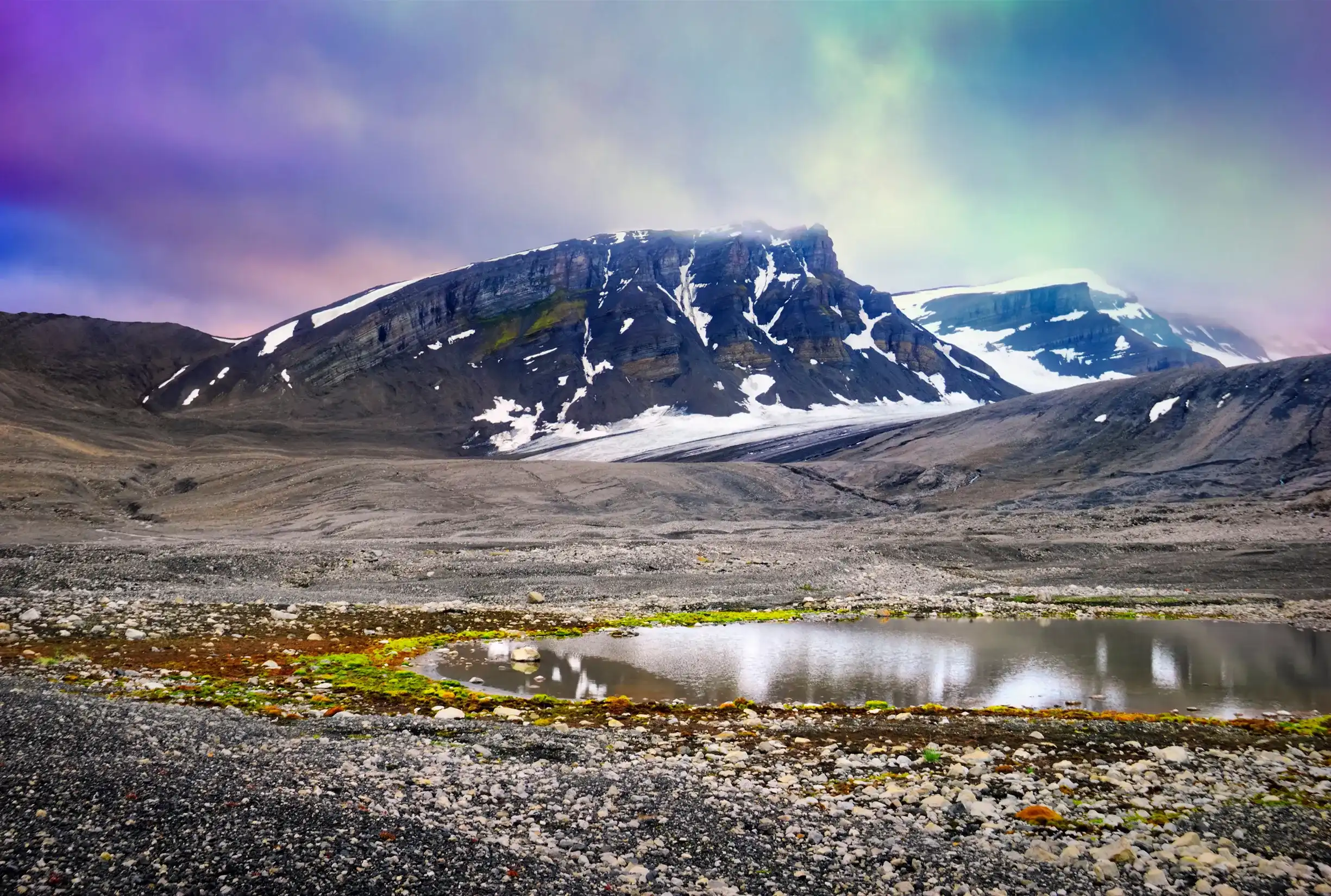 Beautiful scenic view, black rock, snow, pebble and small glacial lake with moss at the background of colorful dramatic sky near Barentsburg, Norway, Spitsbergen island, Svalbard and Jan Mayen Beautiful scenic view, black rock, snow, pebble and small glacial lake with moss at the background of colorful dramatic sky near Barentsburg, Norway, Spitsbergen island, Svalbard and Jan Mayen