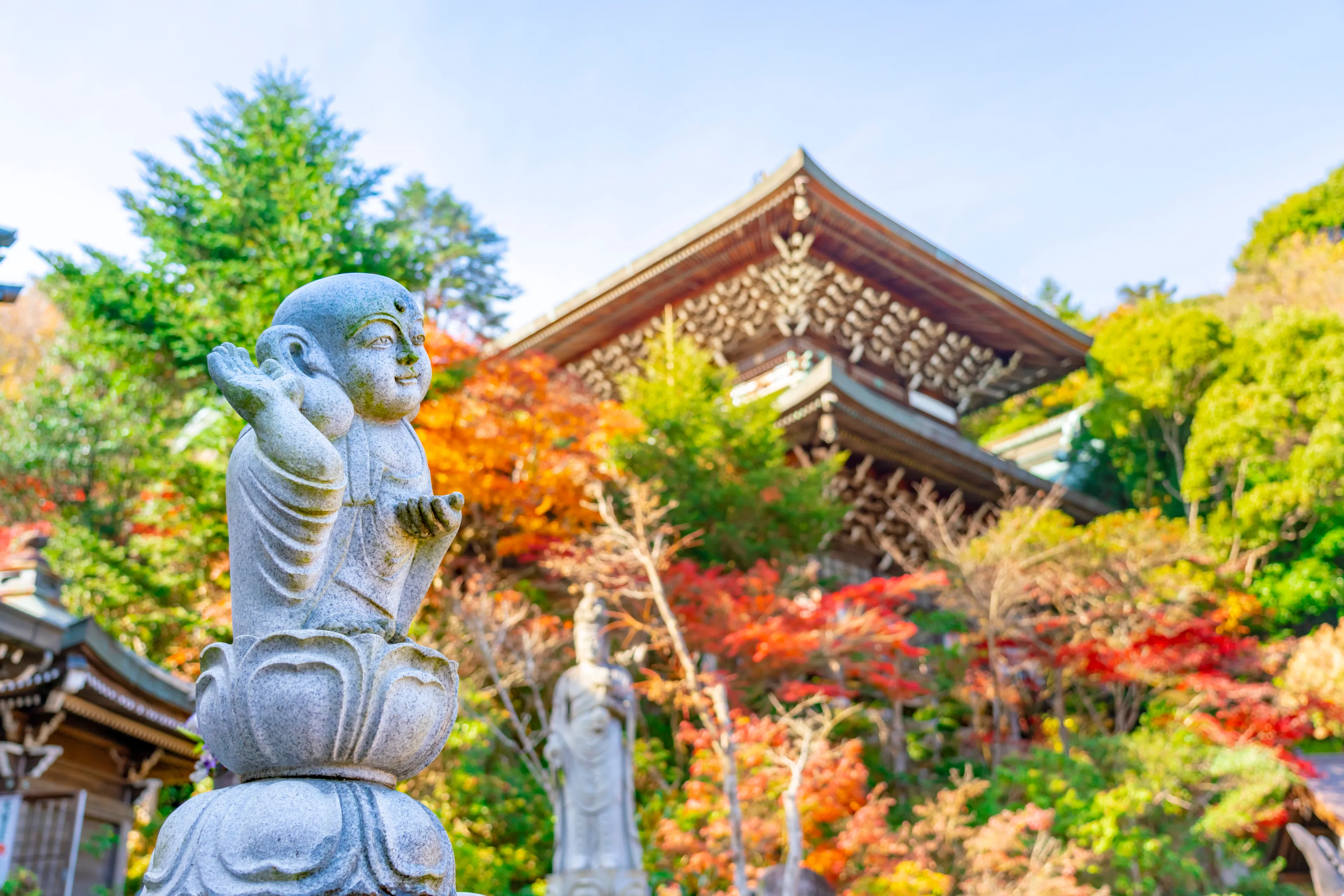 Buddha sculpture in Daishō-in, next to Itsukushima Shrine temple, in front of floating gate, or torii. The complex is listed as a UNESCO World Heritage Site. Miyajima, Hiroshima, Japan.