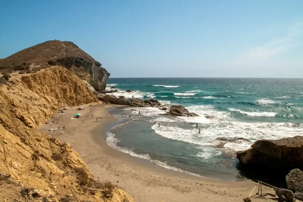 Bathers in Los Amarillos cove in the Mediterranean Sea. Small beach next to Genoveses beach at the end of summer. Nijar, Spain. Bathers in Los Amarillos cove in the Mediterranean Sea. Small beach next to Genoveses beach at the end of summer. Nijar, Spain.