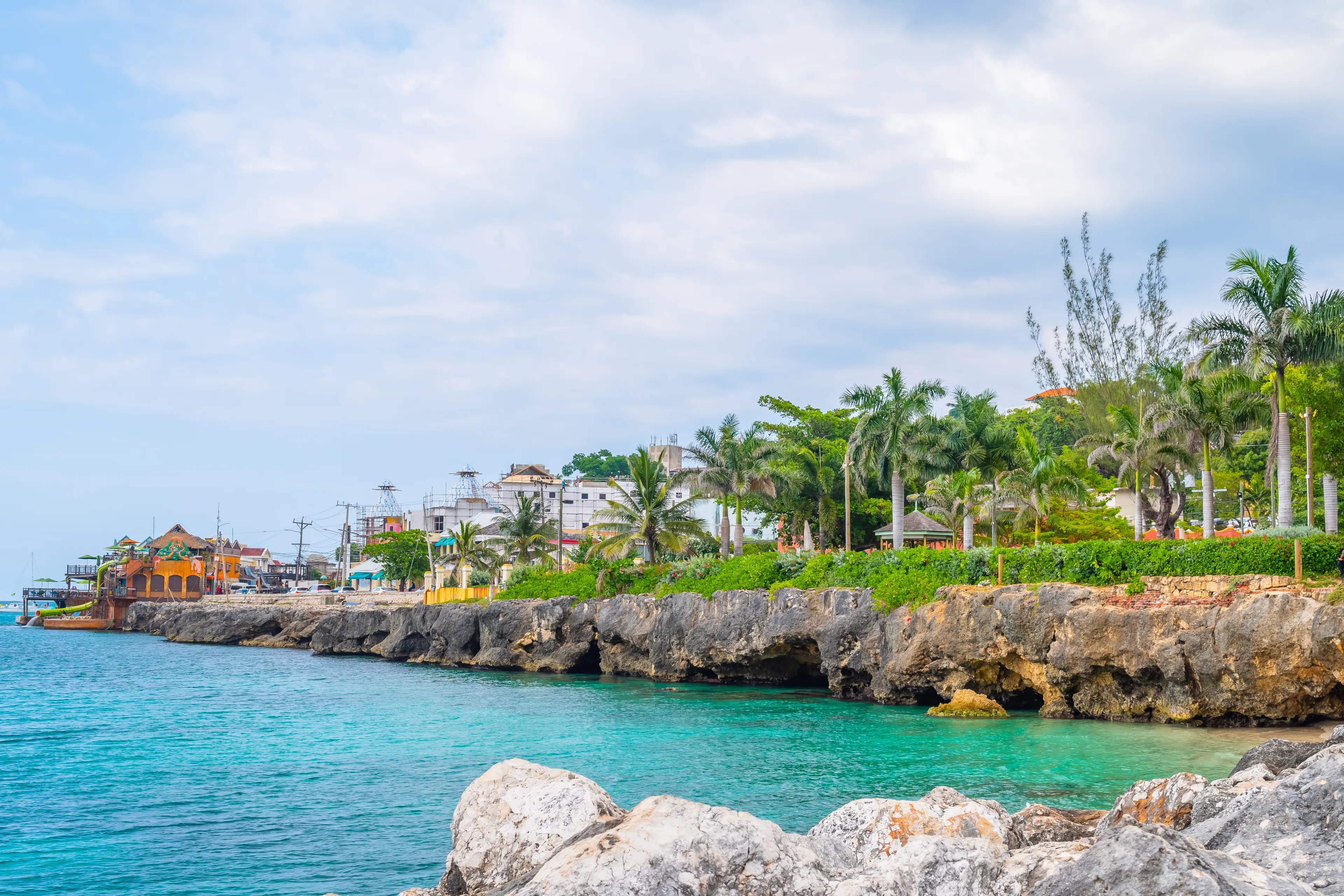 Beautiful coastal cliffside turquoise ocean on Caribbean island. Sunny summer vacation day on the coast of Montego Bay, Jamaica. Ideal tropical tourist destination. Margaritaville in background.