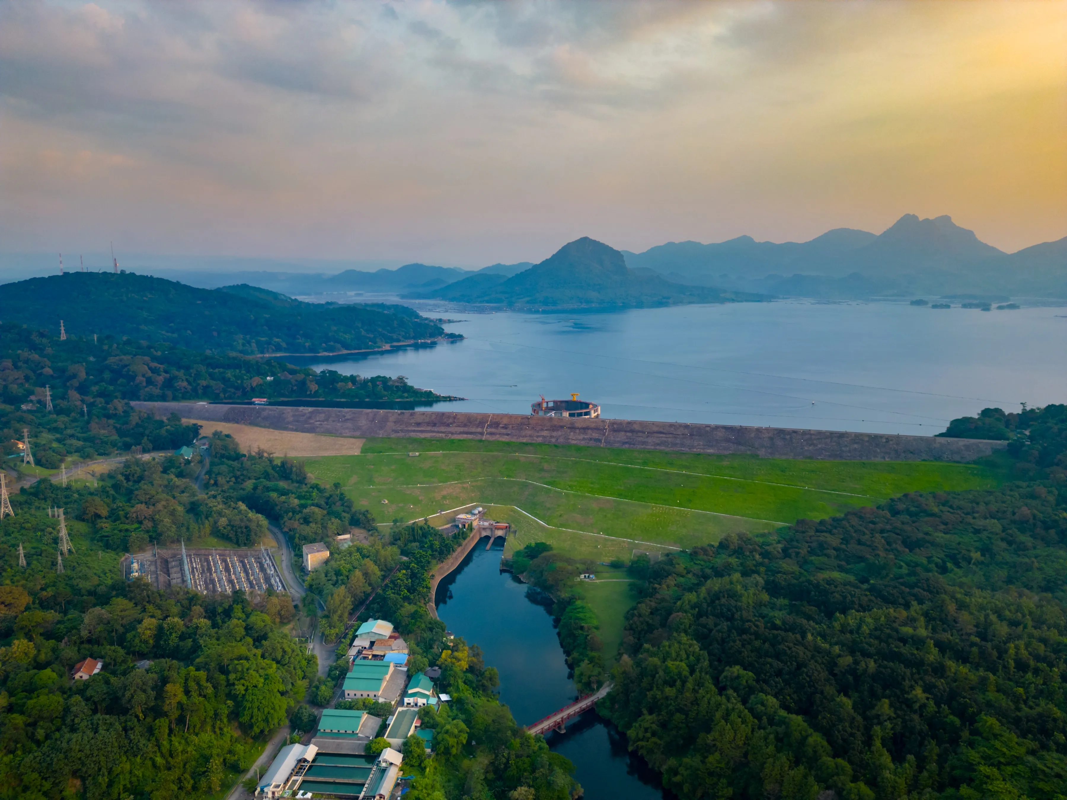 Drone View of Jatiluhur Dam and Reservoir in Purwakarta, Indonesia – Scenic Lake, Green Hills, Hydropower Station, and Mountains at Sunset