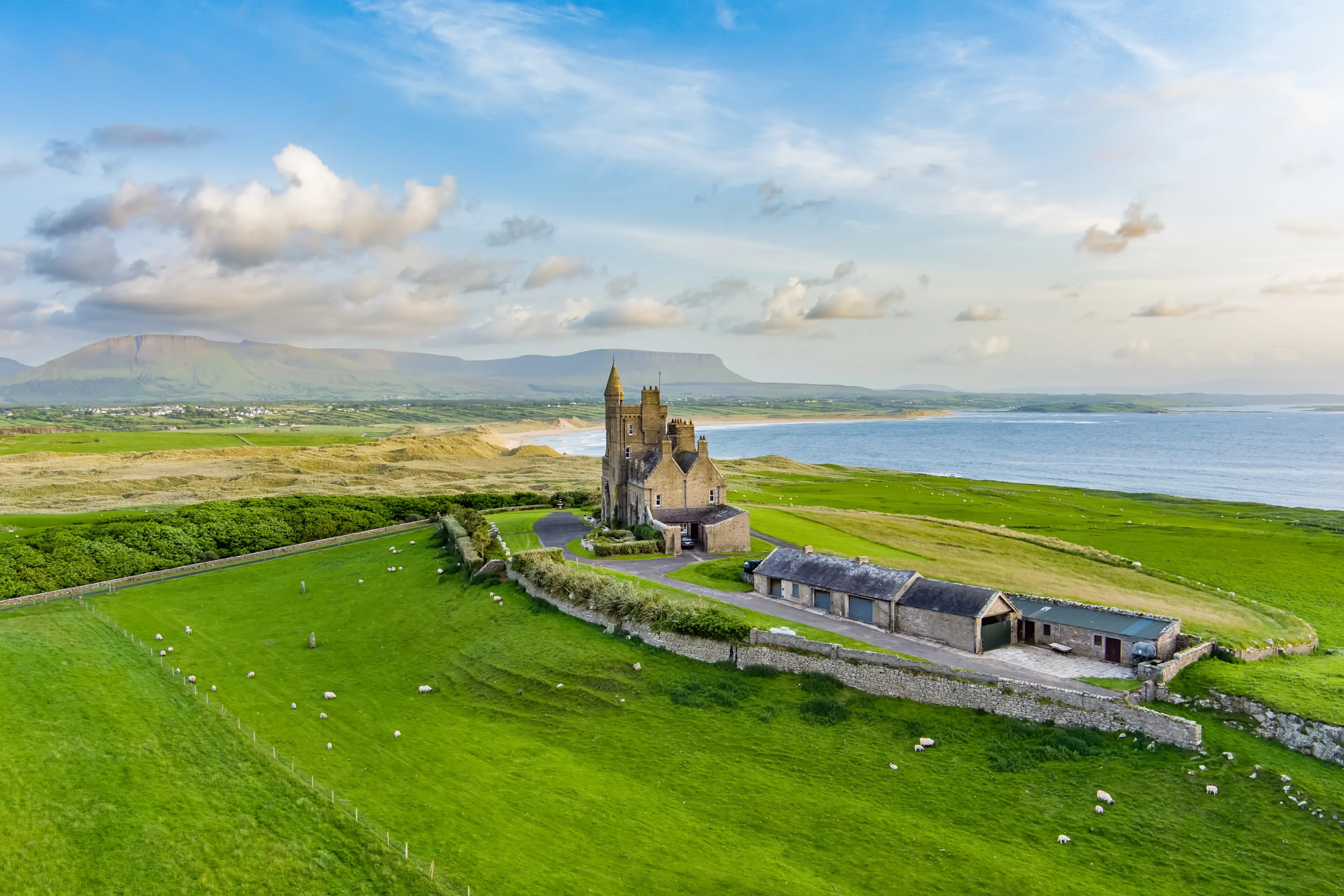 Classiebawn Castle on a backdrop of picturesque landscape of Mullaghmore Head. Spectacular sunset view with huge waves rolling ashore. Signature point of Wild Atlantic Way, Co. Sligo, Ireland