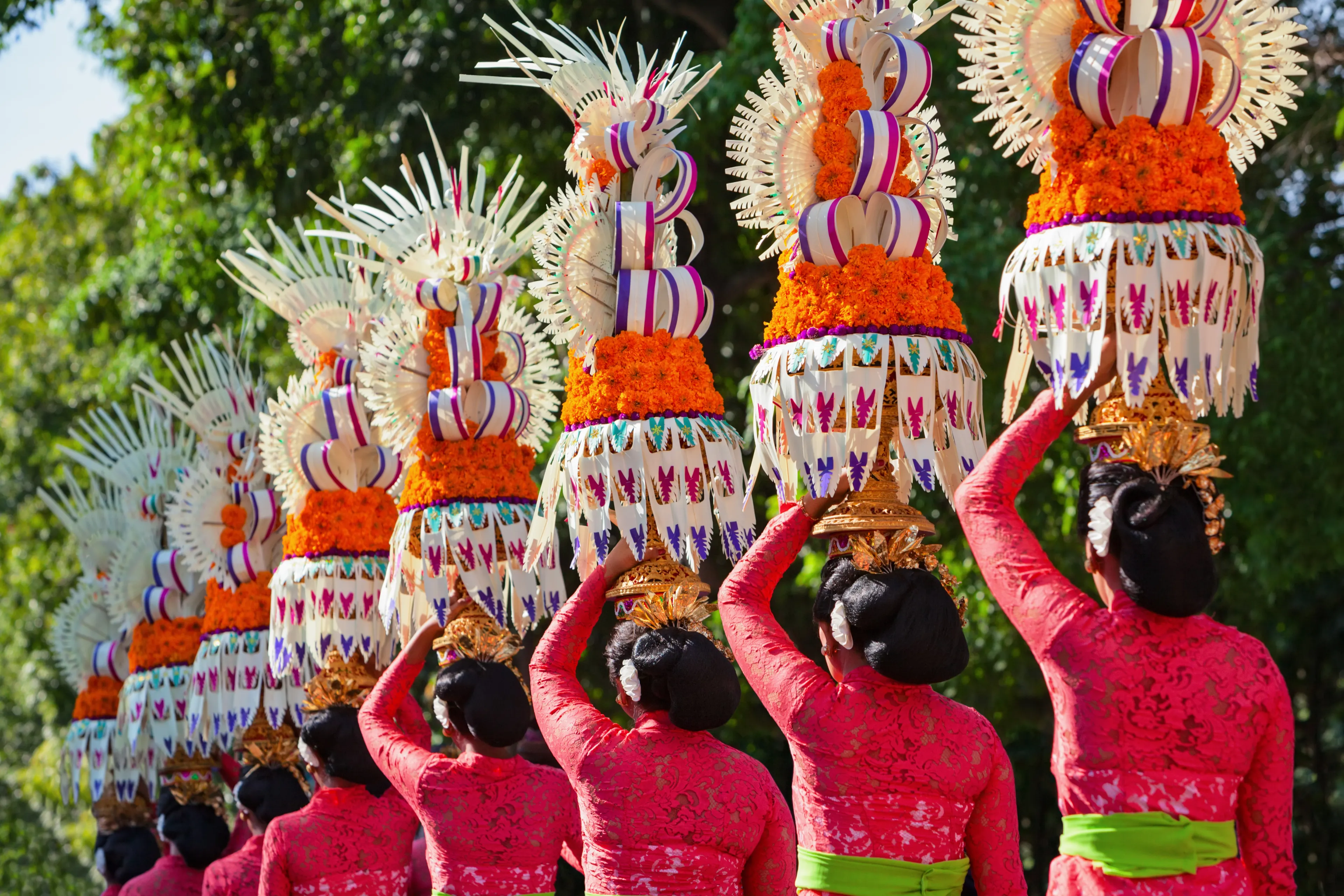 Group of beautiful Balinese women in costumes - sarong, carry offering for Hindu ceremony. Traditional dances, arts festivals, culture of Bali island and Indonesia people. Indonesian travel background