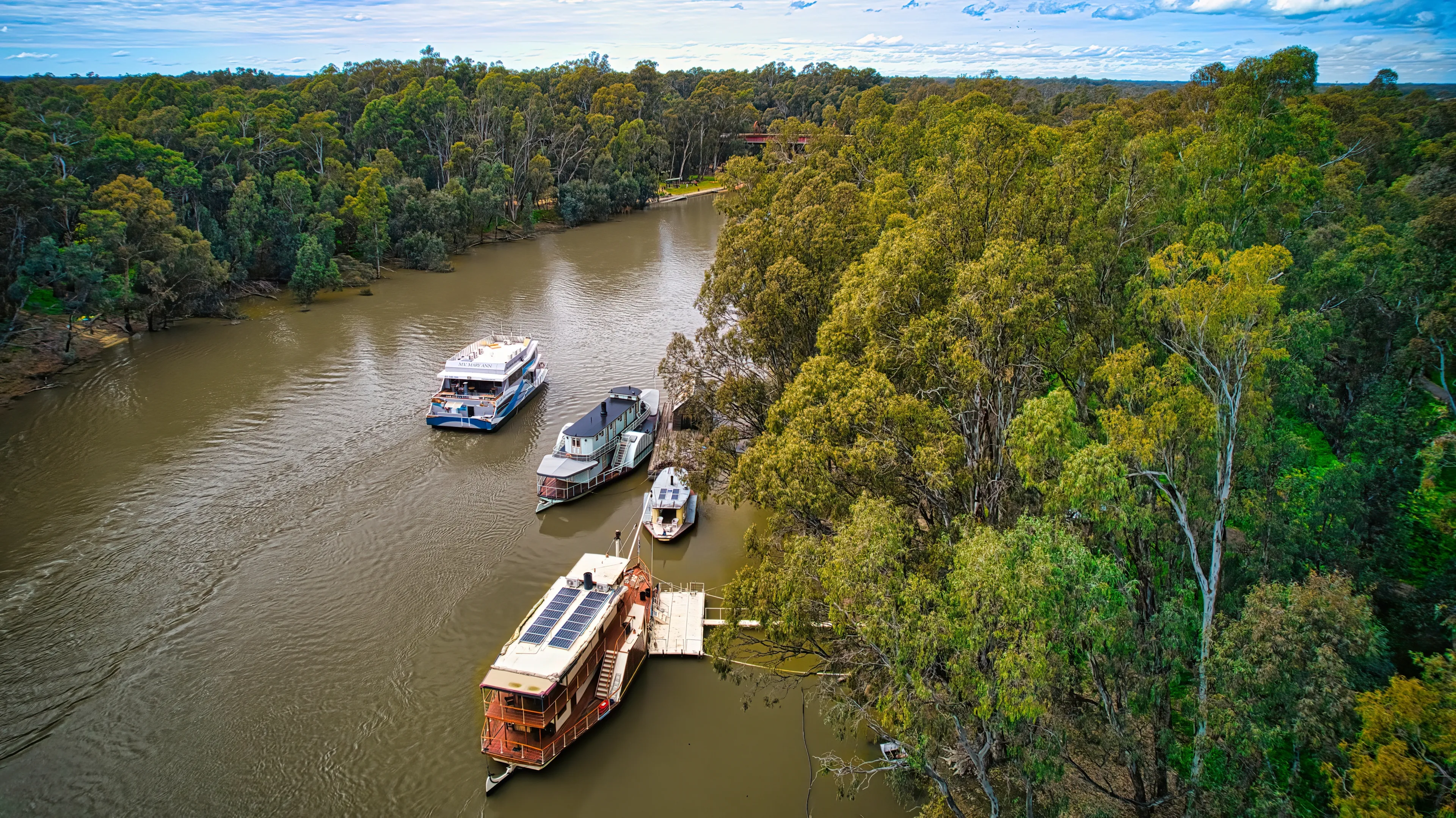 Echuca, Victoria, Australia - 12 August 2022: A cruising boat passing some paddle boats on the Murray River at Echuca Victoria