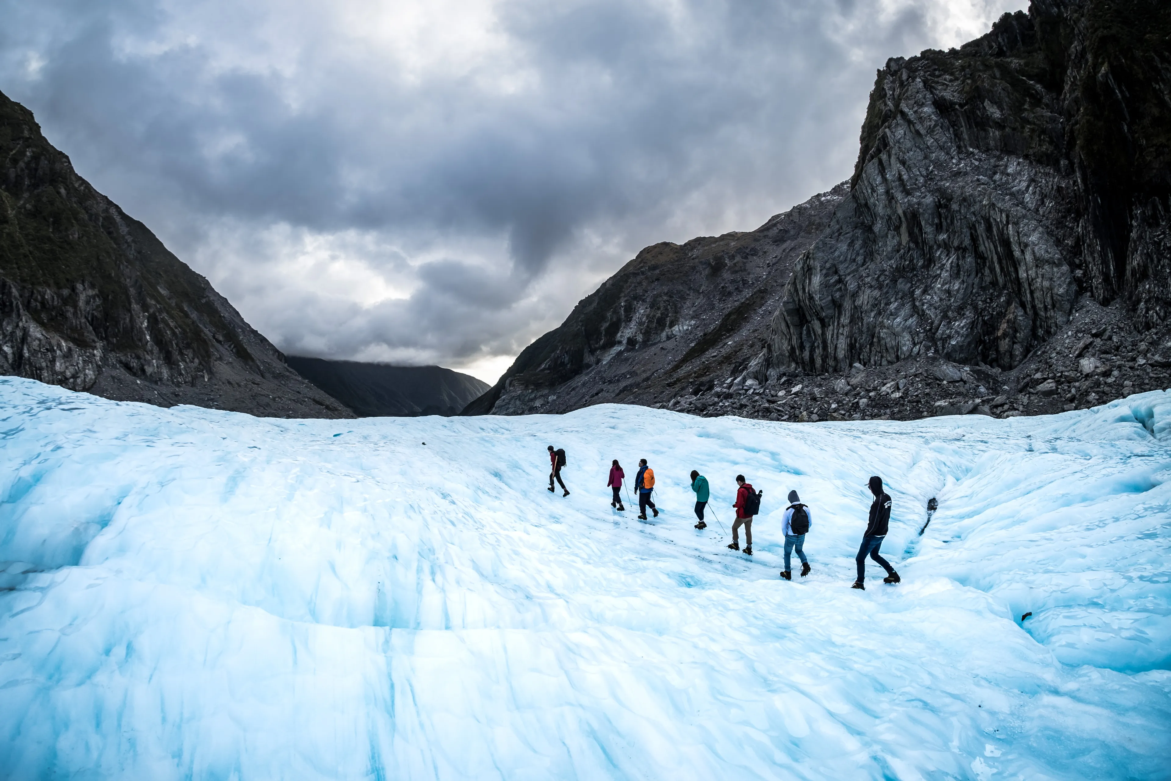 NEW ZEALAND, FOX GLACIER - MAY 2016: Hikers and travelers walking on ice in Fox Glacier, New Zealand. Breathtaking guided glacier walk onto the world-famous Fox Glacier.