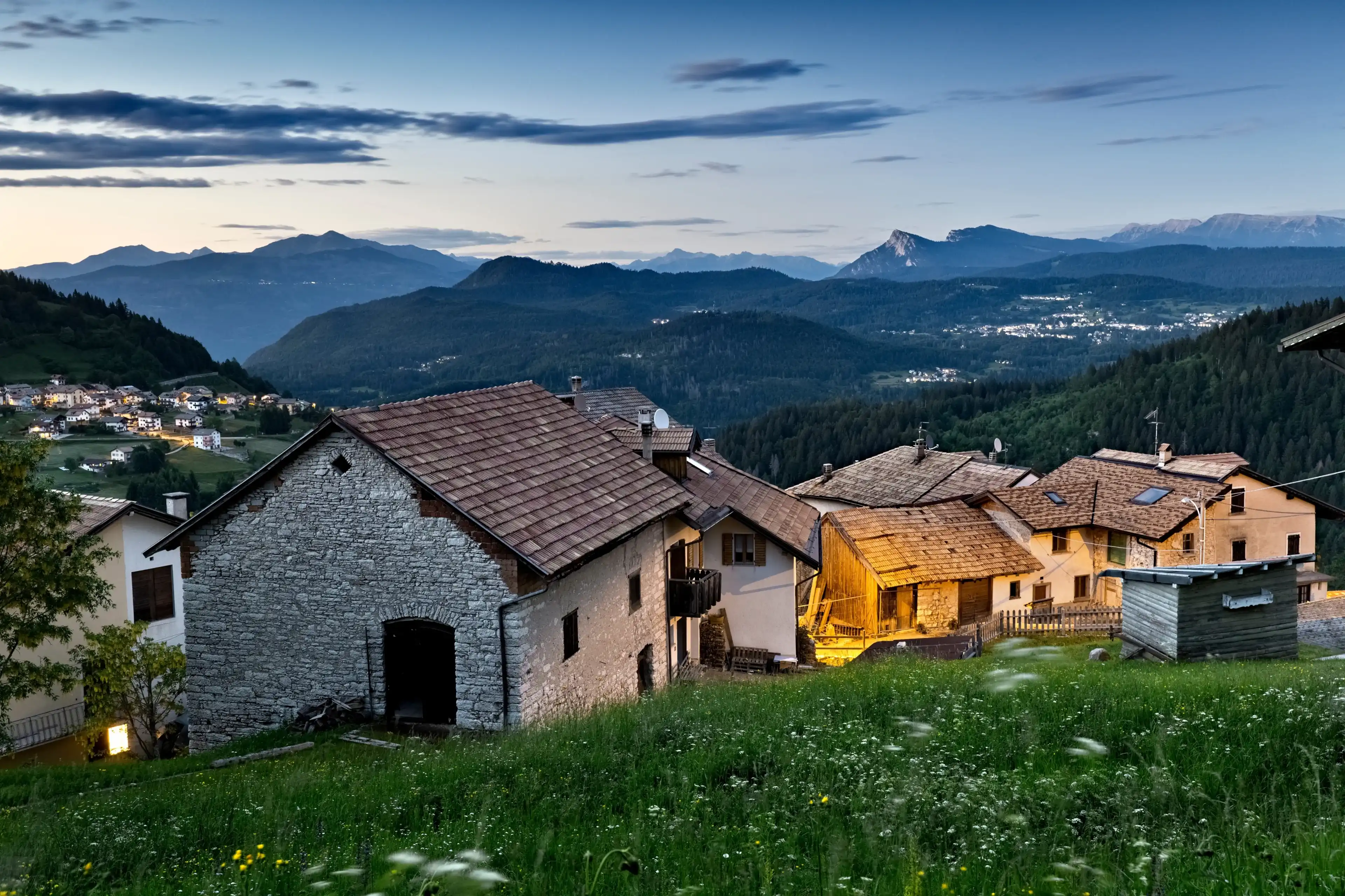 Dusk at the alpine village of Perpruneri. In the background the Lavarone plateau. Folgaria, Alpe Cimbra, Trentino, Italy. Dusk at the alpine village of Perpruneri. In the background the Lavarone plateau. Folgaria, Alpe Cimbra, Trentino, Italy.
