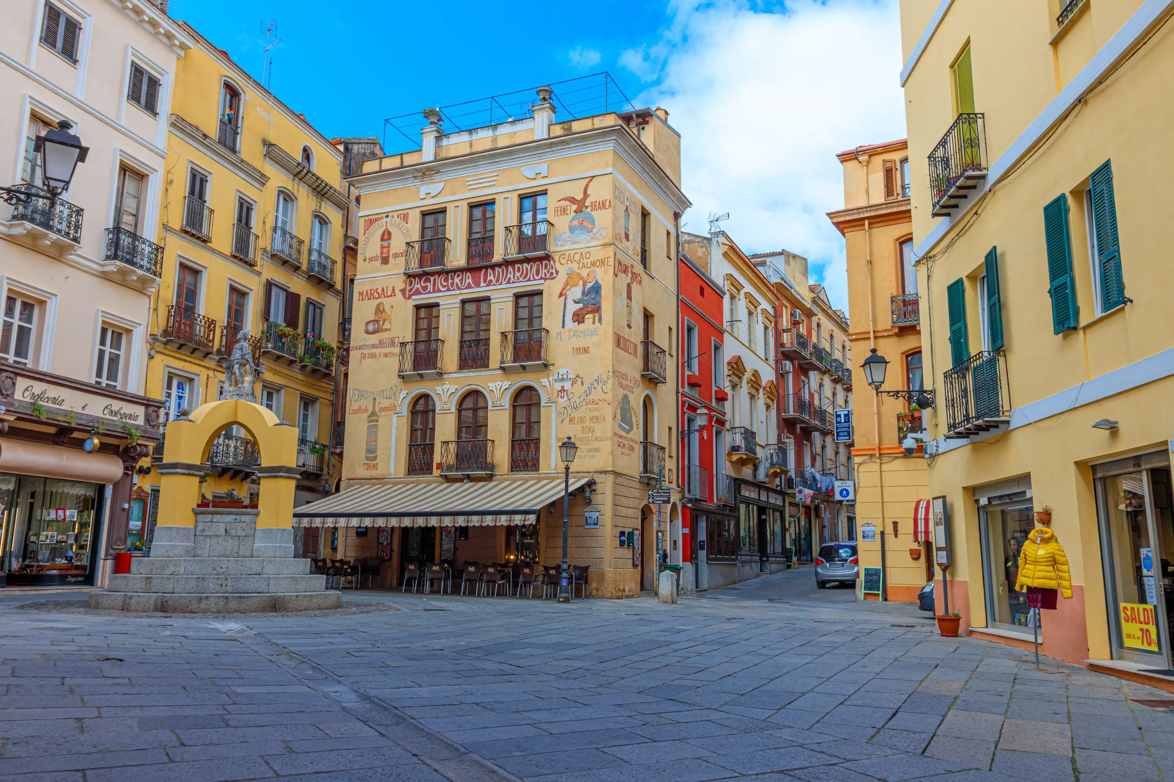 Iglesias, Italy - 03 13 2024: Facade of pastry shop "Pasticceria Lamarmora" and Maimoni fountain Iglesias, Italy - 03 13 2024: Facade of pastry shop "Pasticceria Lamarmora" and Maimoni fountain