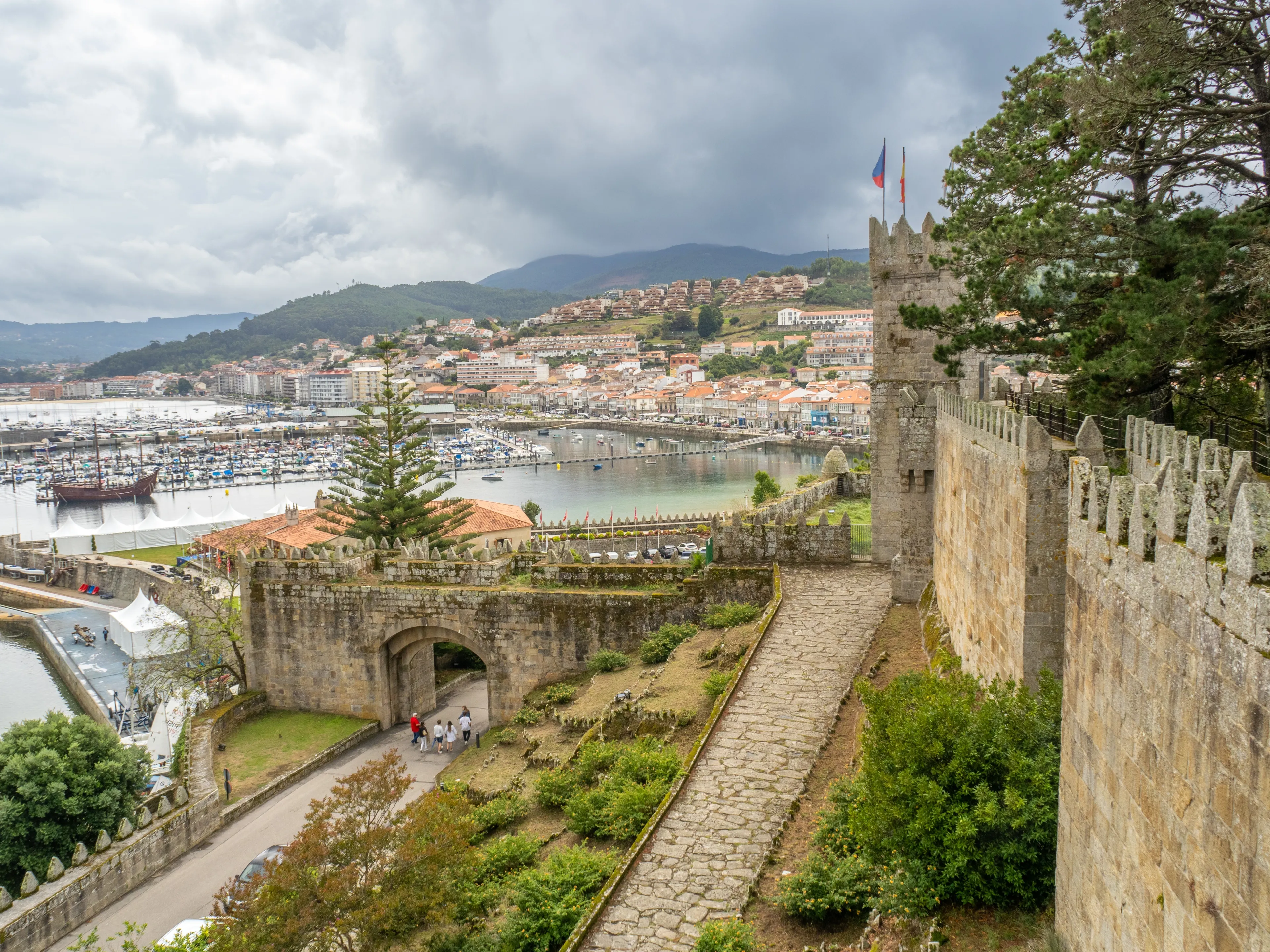 Breathtaking view of Baiona's port from Parador de Baiona, Pontevedra. Serene waters, charming boats, and historic architecture create a picturesque scene.