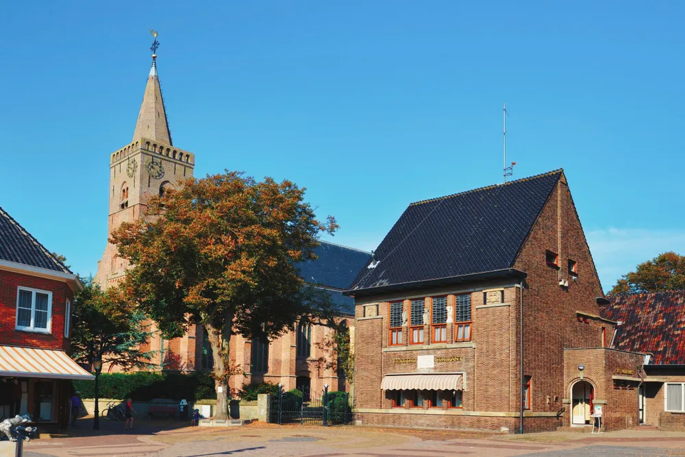 Den Burg, Texel / Netherlands - August 2019: Marketplace in city center of town Den Burg with old brick stone buildings and protestant church with clock tower