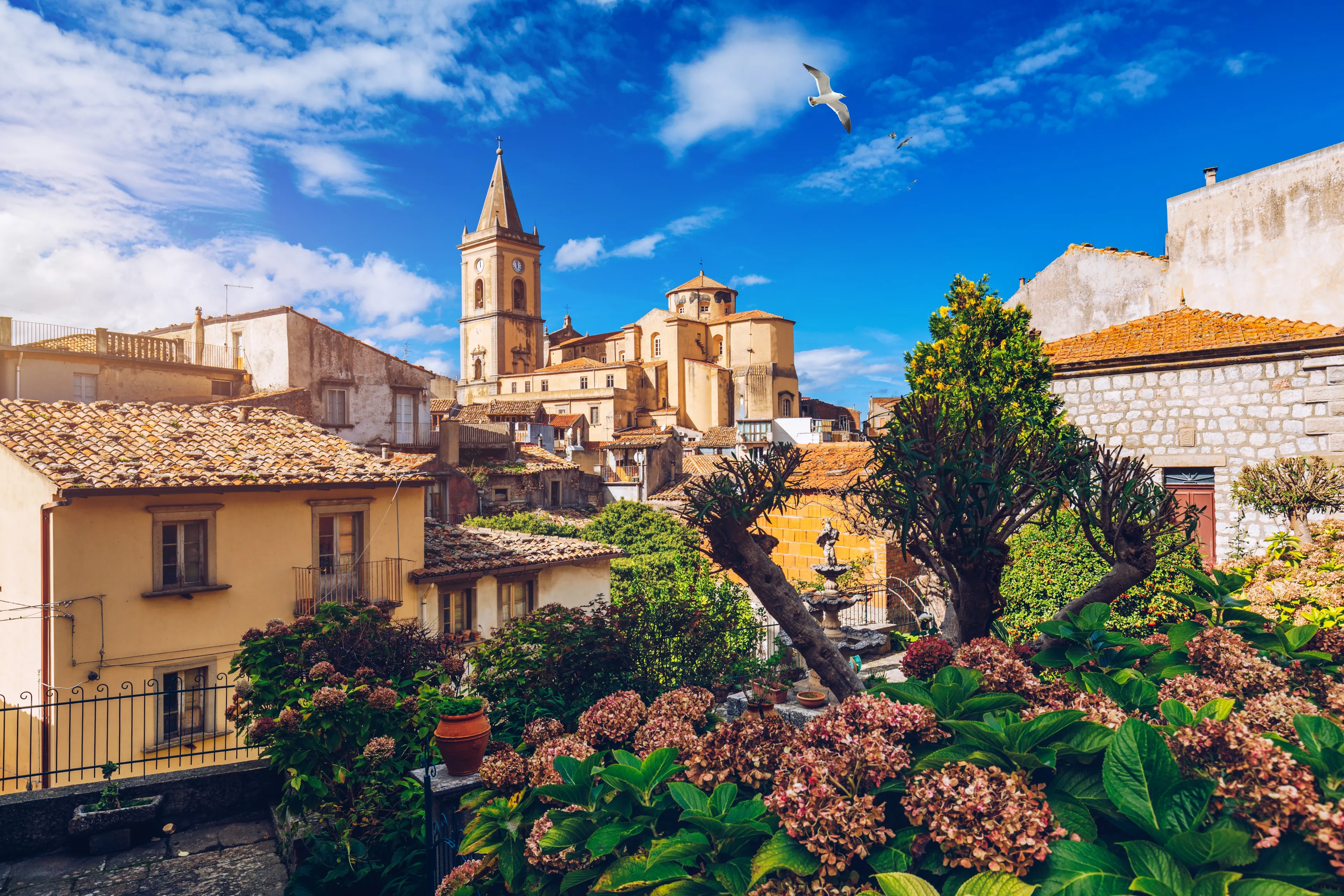 Picturesque street with the Duomo in the background in Novara di Sicilia, Sicily, Italy. Amazing cityscape of Novara di Sicilia town. Mountain village Novara di Sicilia, Sicily, Italy.