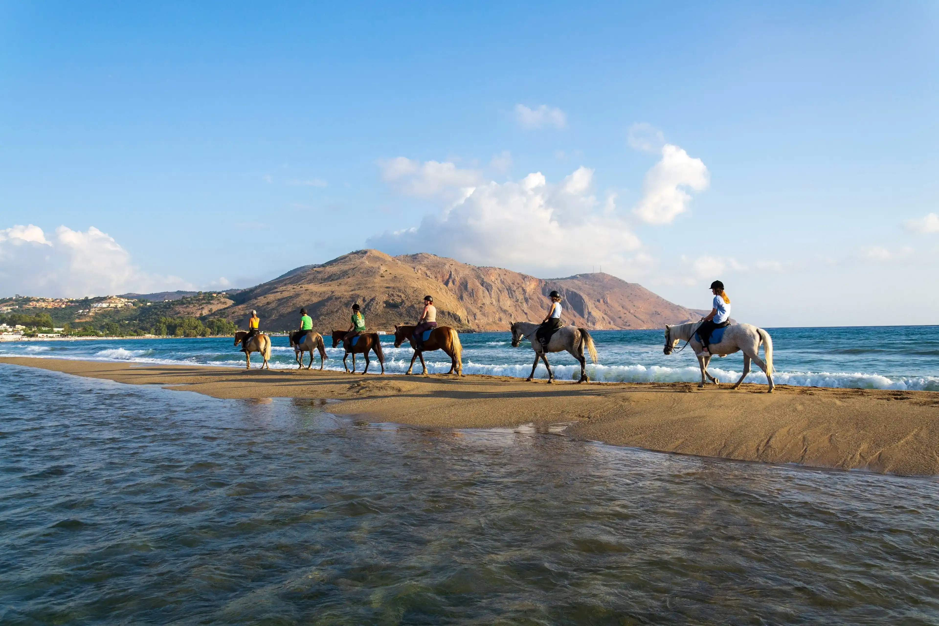 GEORGIOUPOLI, GREECE – AUGUST 8 2022: Young women riding horses on the beach at dawn on August 8, 2022 in Georgioupoli, Greece. GEORGIOUPOLI, GREECE – AUGUST 8 2022: Young women riding horses on the beach at dawn on August 8, 2022 in Georgioupoli, Greece.