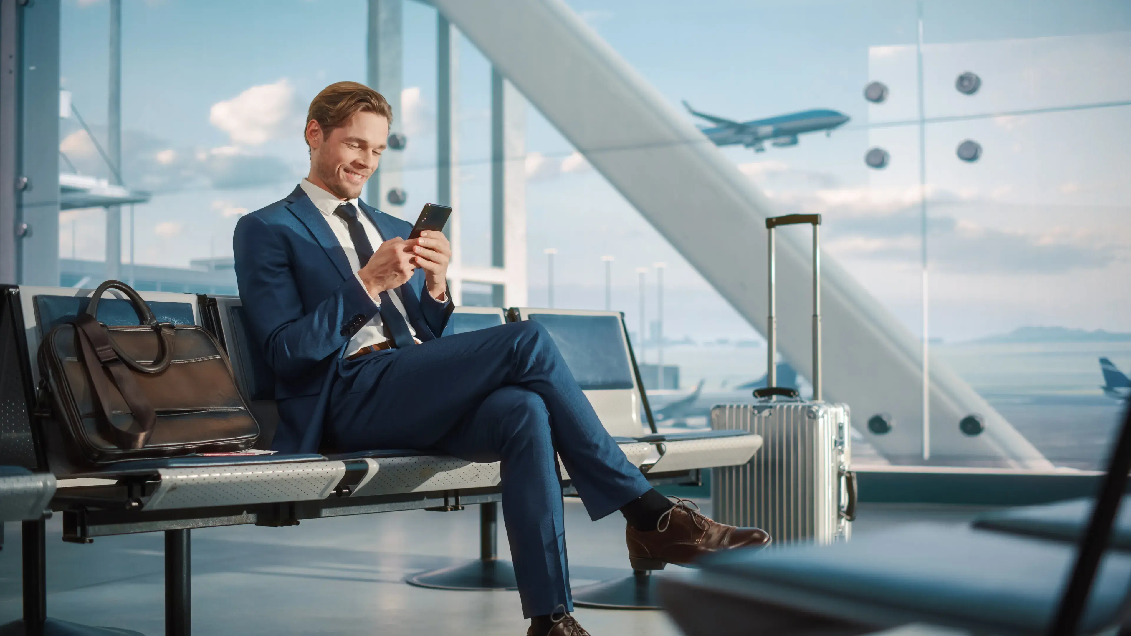 Airport Terminal Flight Wait: Smiling Businessman Uses Smartphone for e-Business Airport Terminal Flight Wait: Smiling Businessman Uses Smartphone for e-Business
