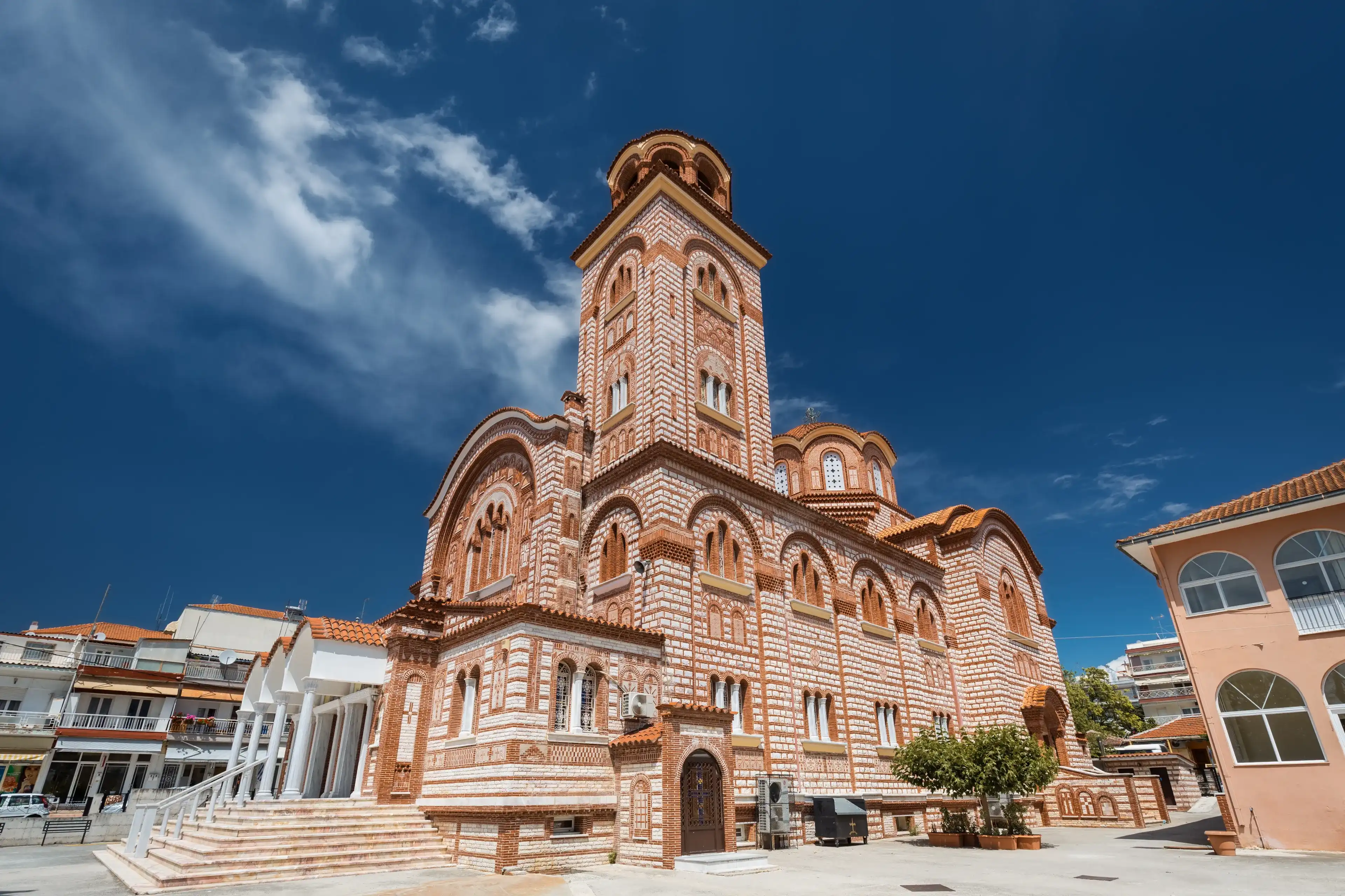 Nea Kallikrateia, Greece - MAY 28 2021: Giant Greek Orthodox cathedral against vivid blue sky in a small Mediterranean town near Thessaloniki Nea Kallikrateia, Greece - MAY 28 2021: Giant Greek Orthodox cathedral against vivid blue sky in a small Mediterranean town near Thessaloniki