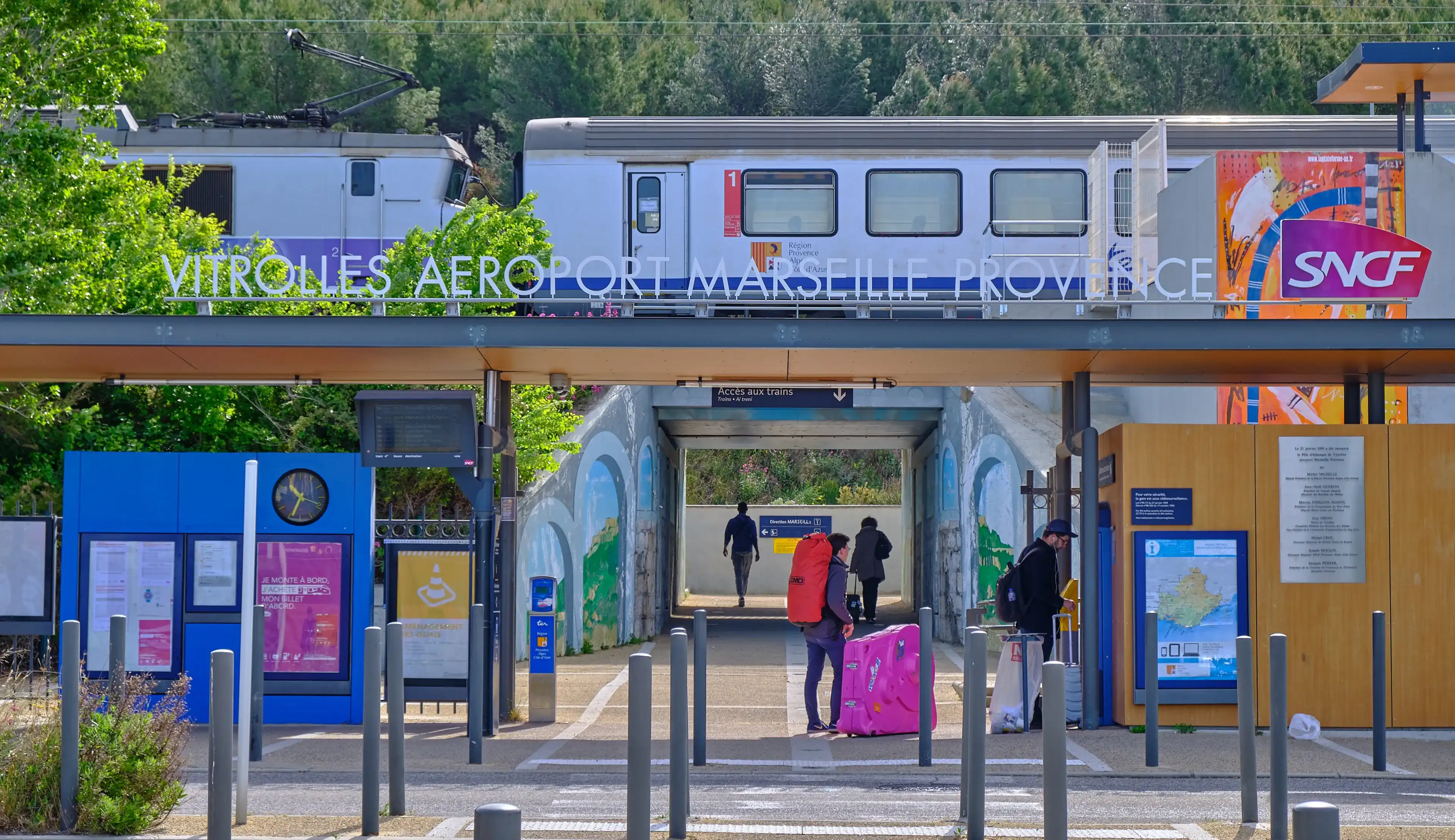 Vitrolles, France, April 28, 2019 : Passenger entering the train station serving the Marseille airport, with a TER train in station on elevated tracks Vitrolles, France, April 28, 2019 : Passenger entering the train station serving the Marseille airport, with a TER train in station on elevated tracks