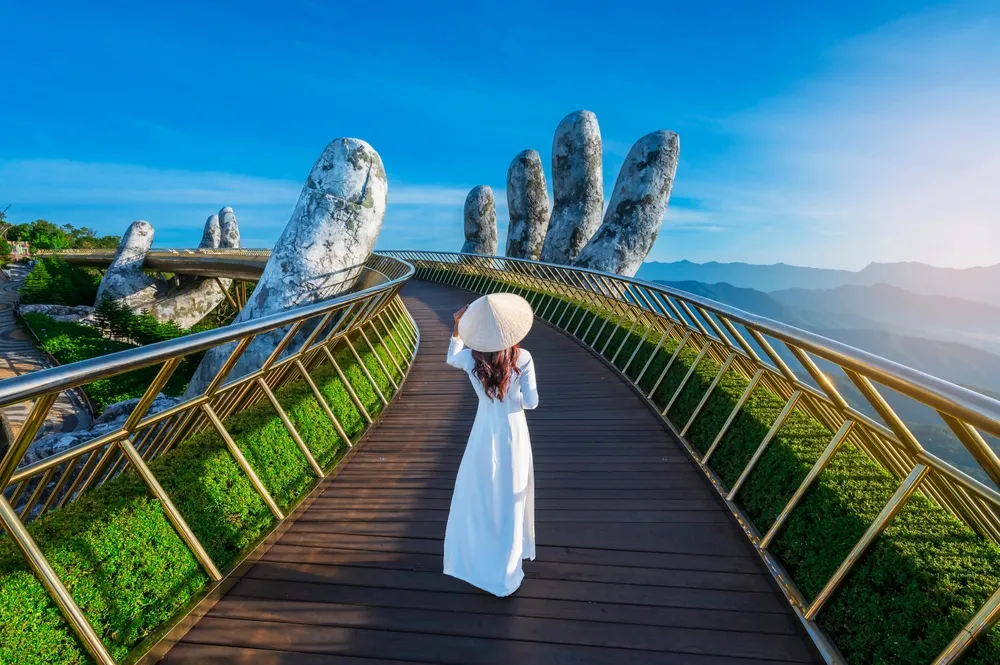 Vietnamese girl with traditional dress (ao dai) on Golden bridge at the top of the Ba Na Hills, Vietnam