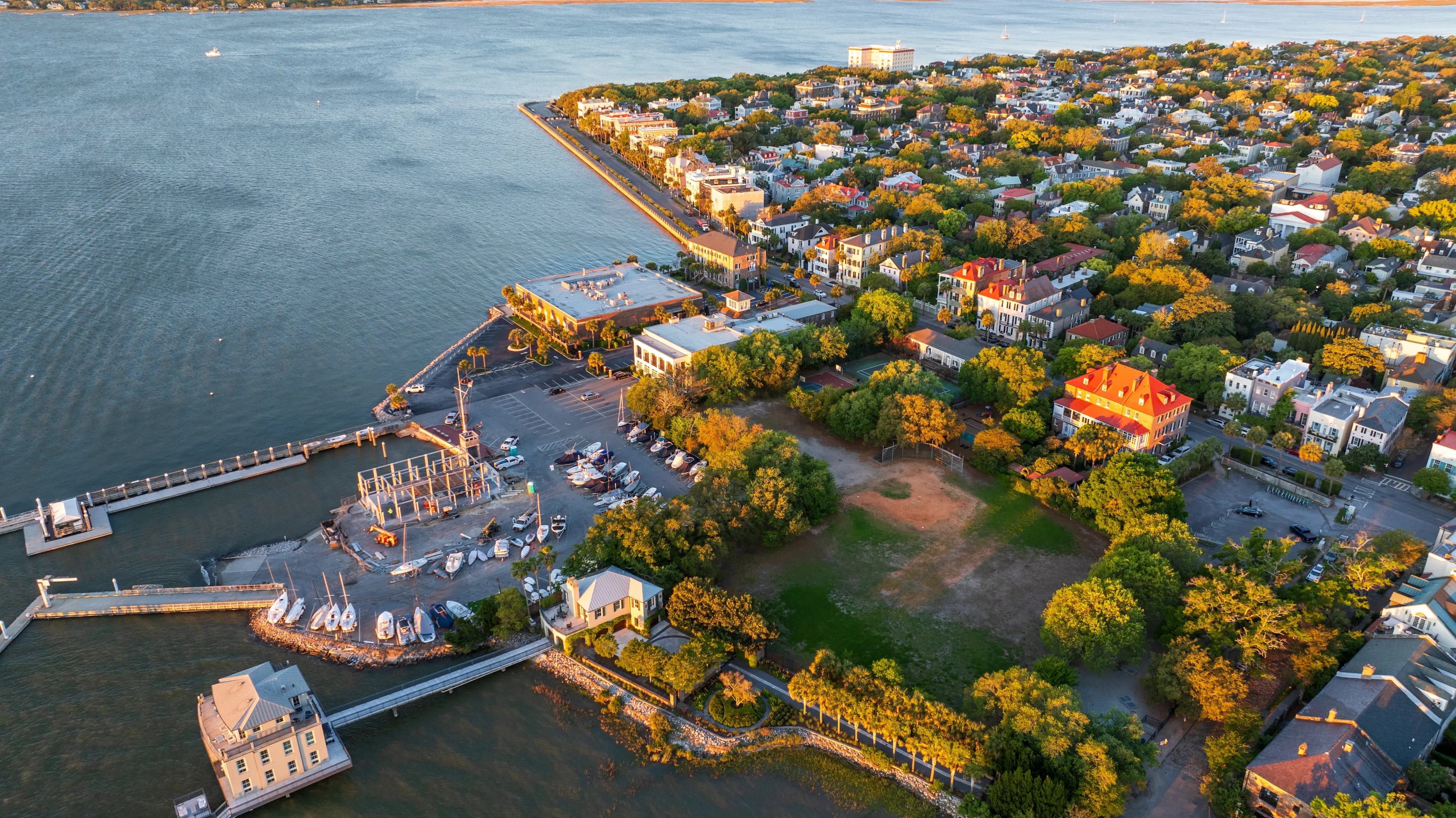 Golden sunrise light bathes downtown Charleston, South Carolina, with historic buildings and streets visible from an aerial view.