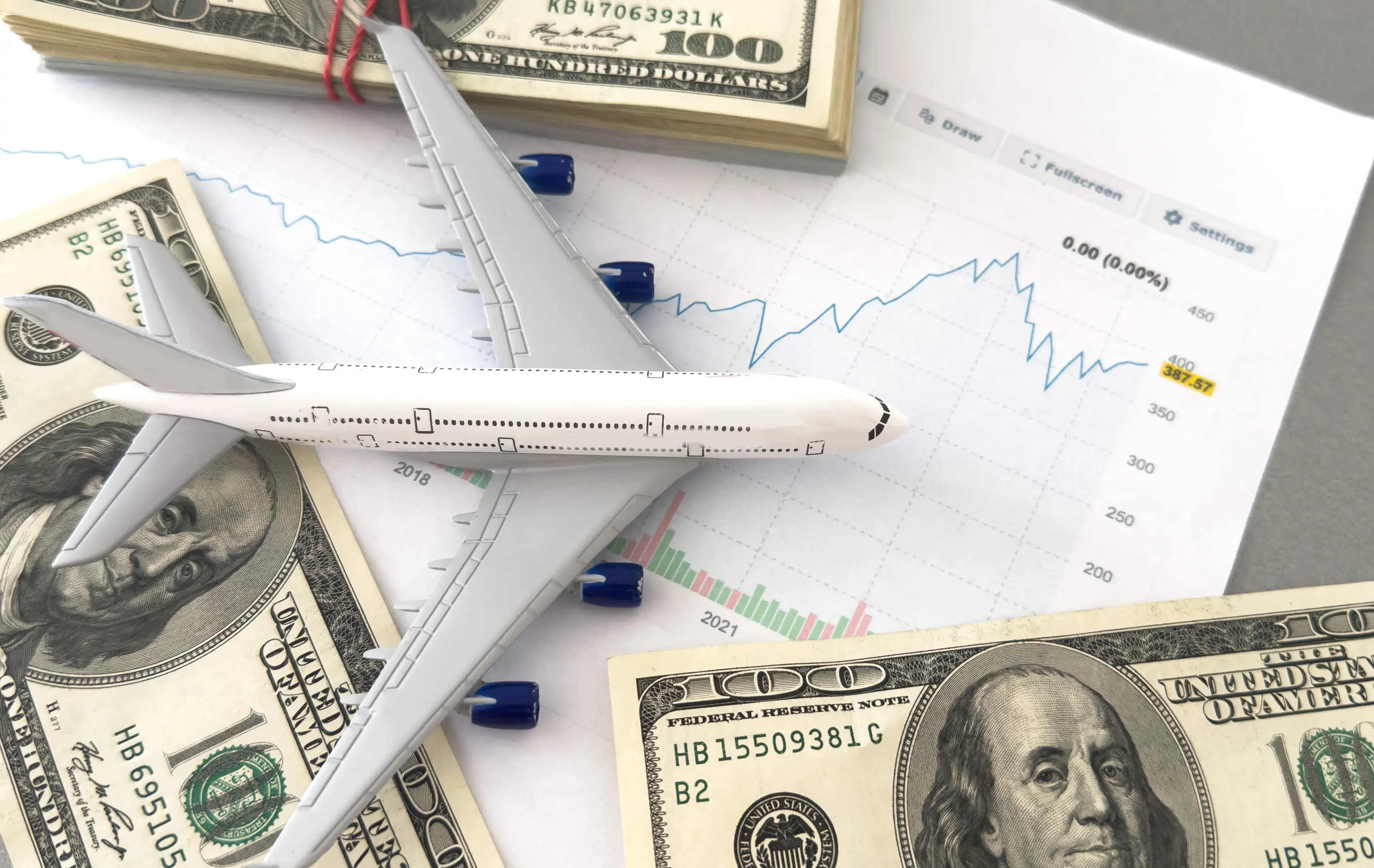 american banknotes and figure of a white plane on a downward trending graph american banknotes and figure of a white plane on a downward trending graph
