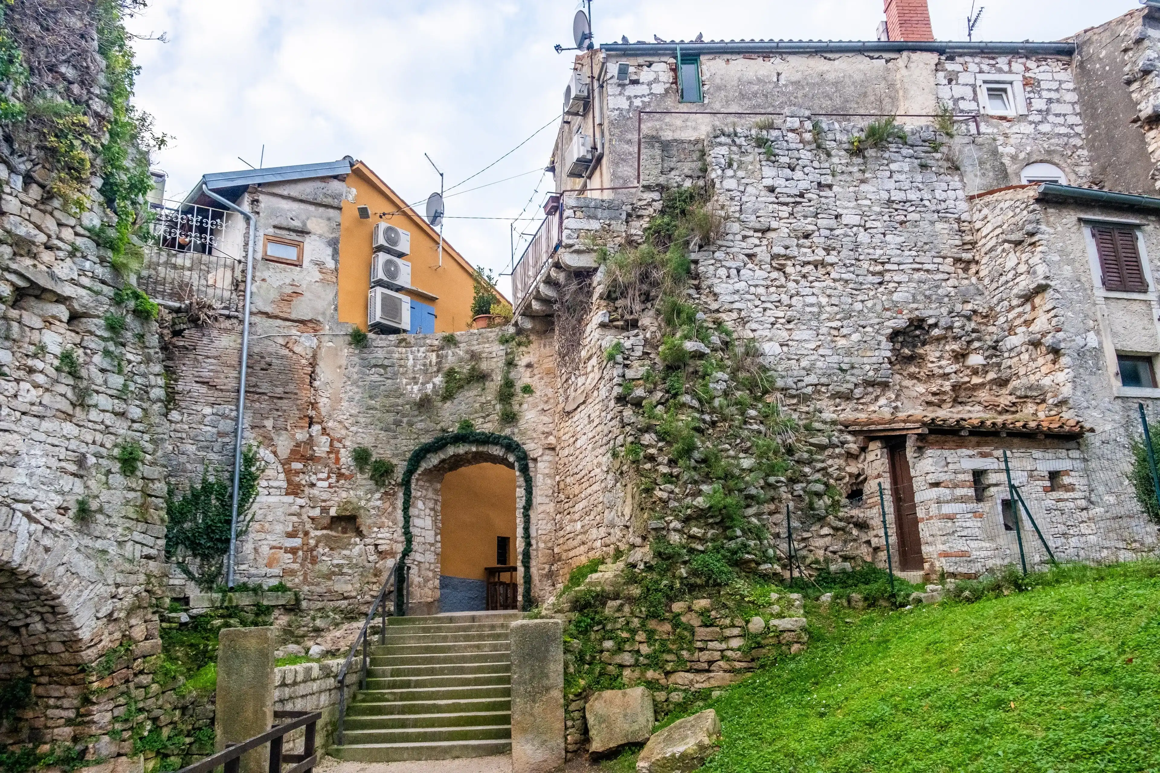 Poreč, Croatia, December 31st, 2023: Historic stone buildings with a charming archway and steps, showcasing the character of Poreč's old town. Poreč, Croatia, December 31st, 2023: Historic stone buildings with a charming archway and steps, showcasing the character of Poreč's old town.