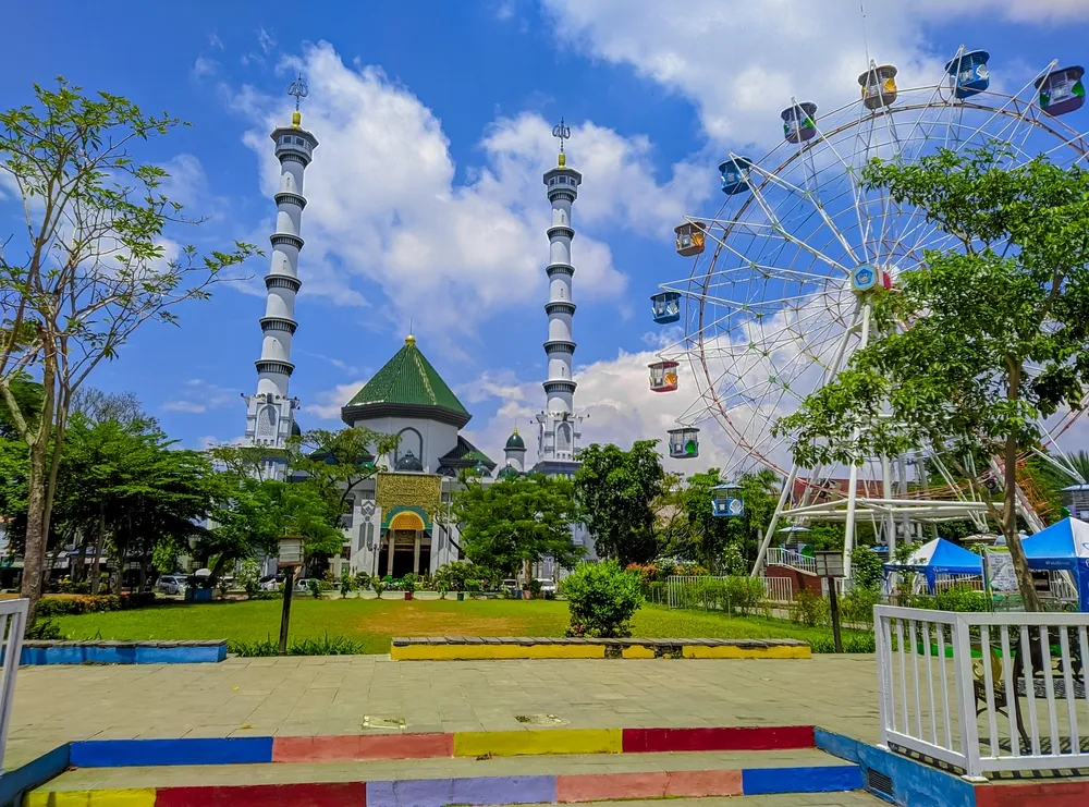 Lamongan, Indonesia - February 15, 2024 : Mosque tower in Lamongan city square with playground in the background