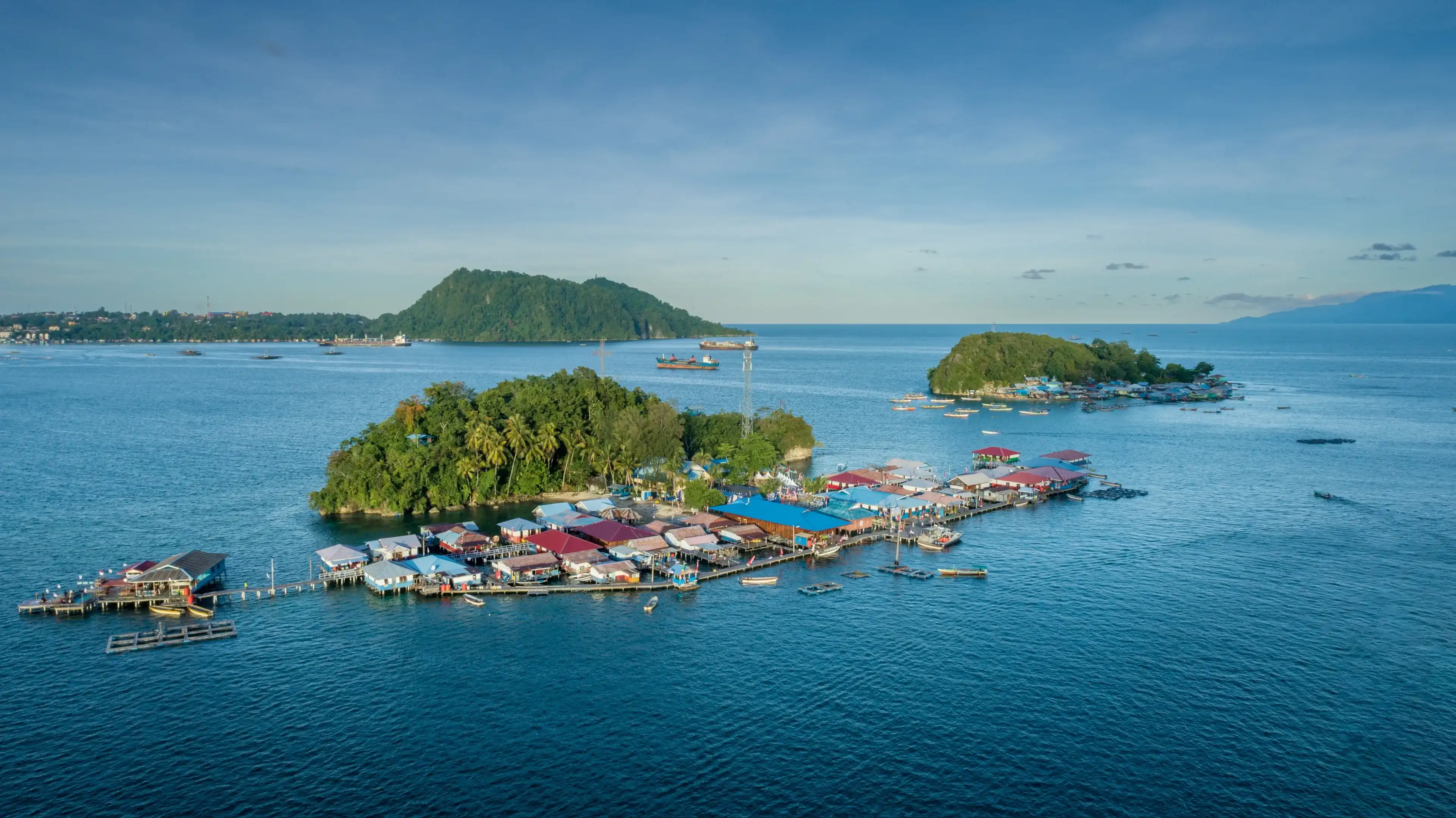 A fishing village on small islands in Jayapura, Papua, Indonesia. The village is above the sea, under clear and cloudy skies, with boats and fishing gear around A fishing village on small islands in Jayapura, Papua, Indonesia. The village is above the sea, under clear and cloudy skies, with boats and fishing gear around