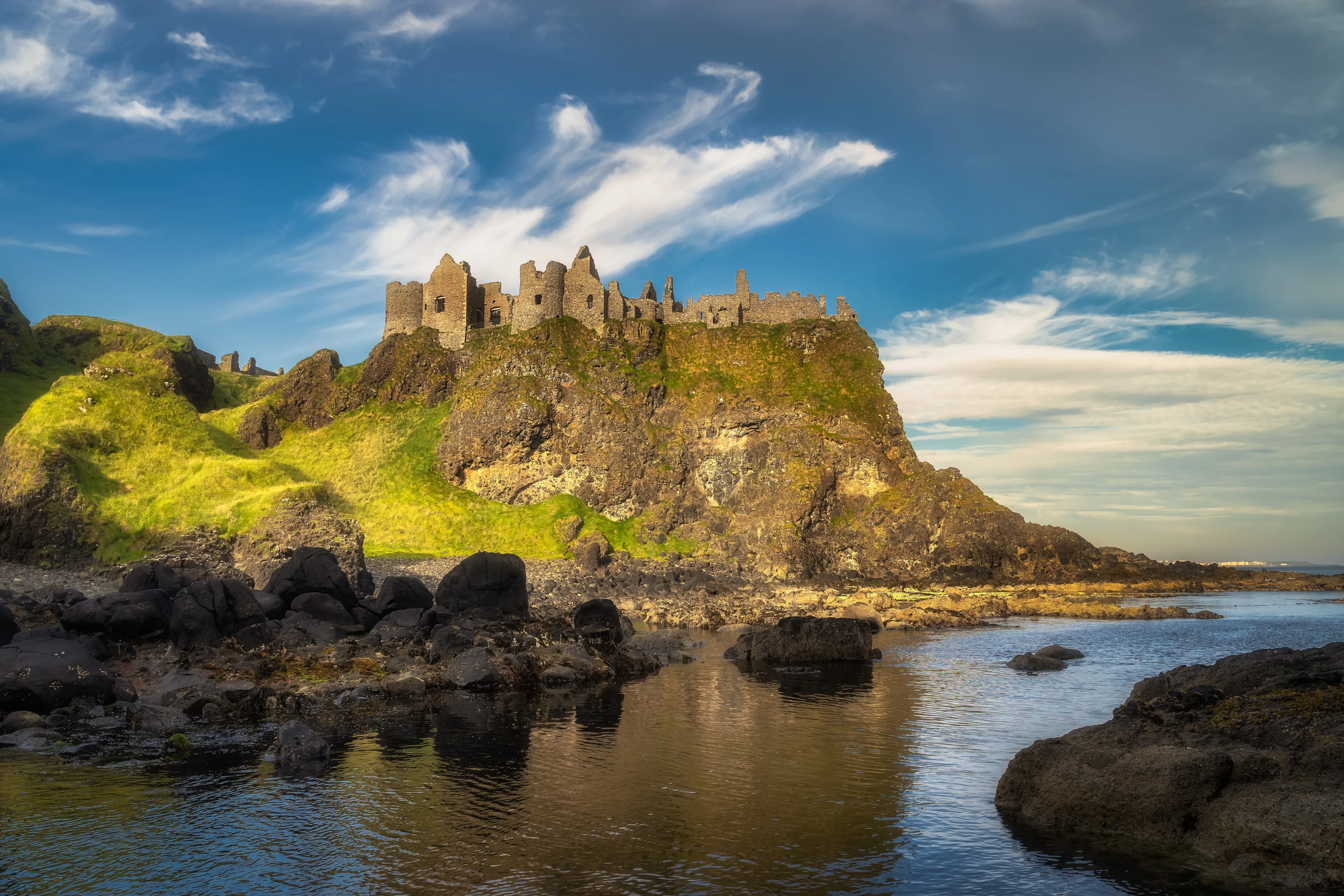 View from a shoreline on Dunluce Castle nested on the edge of cliff, part of Wild Atlantic Way, Northern Ireland. Filming location of popular TV show